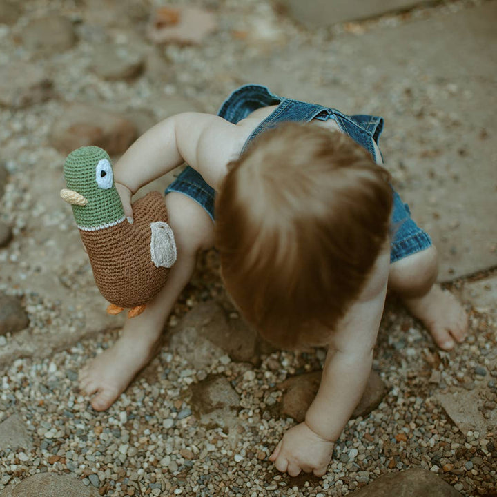 Child playing with a toy on a rocky surface