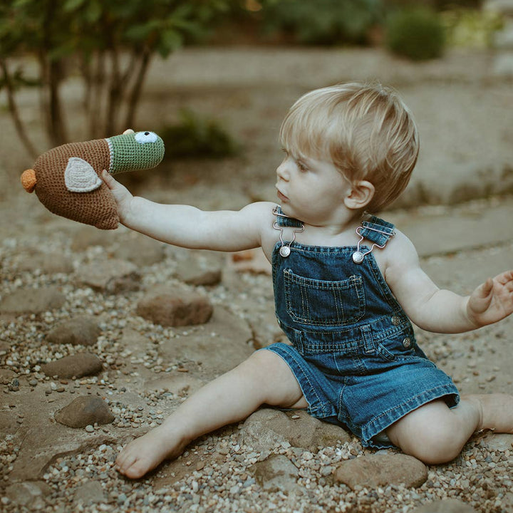 Child playing with a toy outdoors on a gravel path
