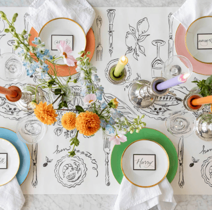 Decorative table setting with floral arrangements, plates, and cutlery on a patterned tablecloth.