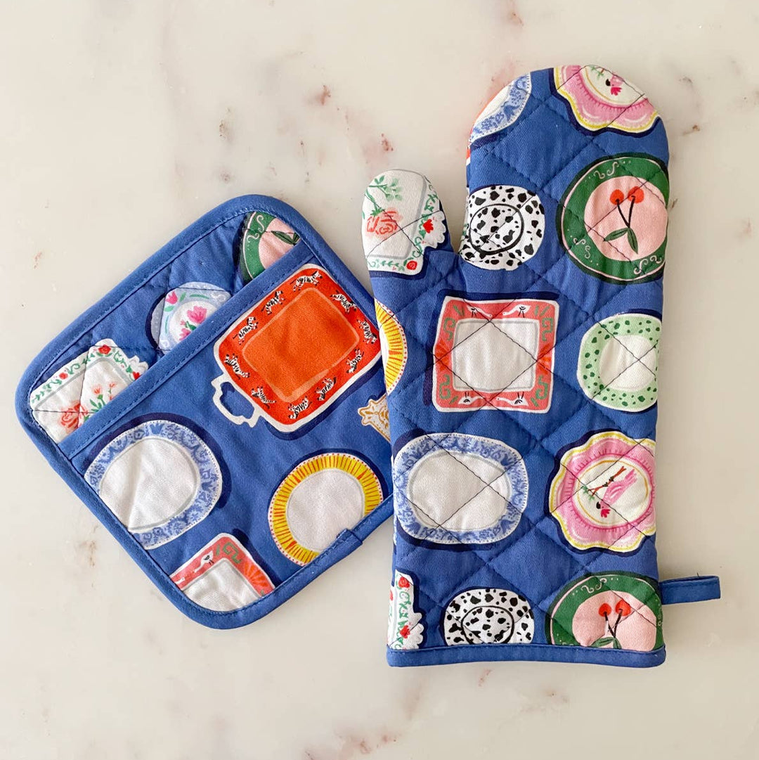 Set of blue oven mitt and pot holder with decorative plate designs on a marble surface