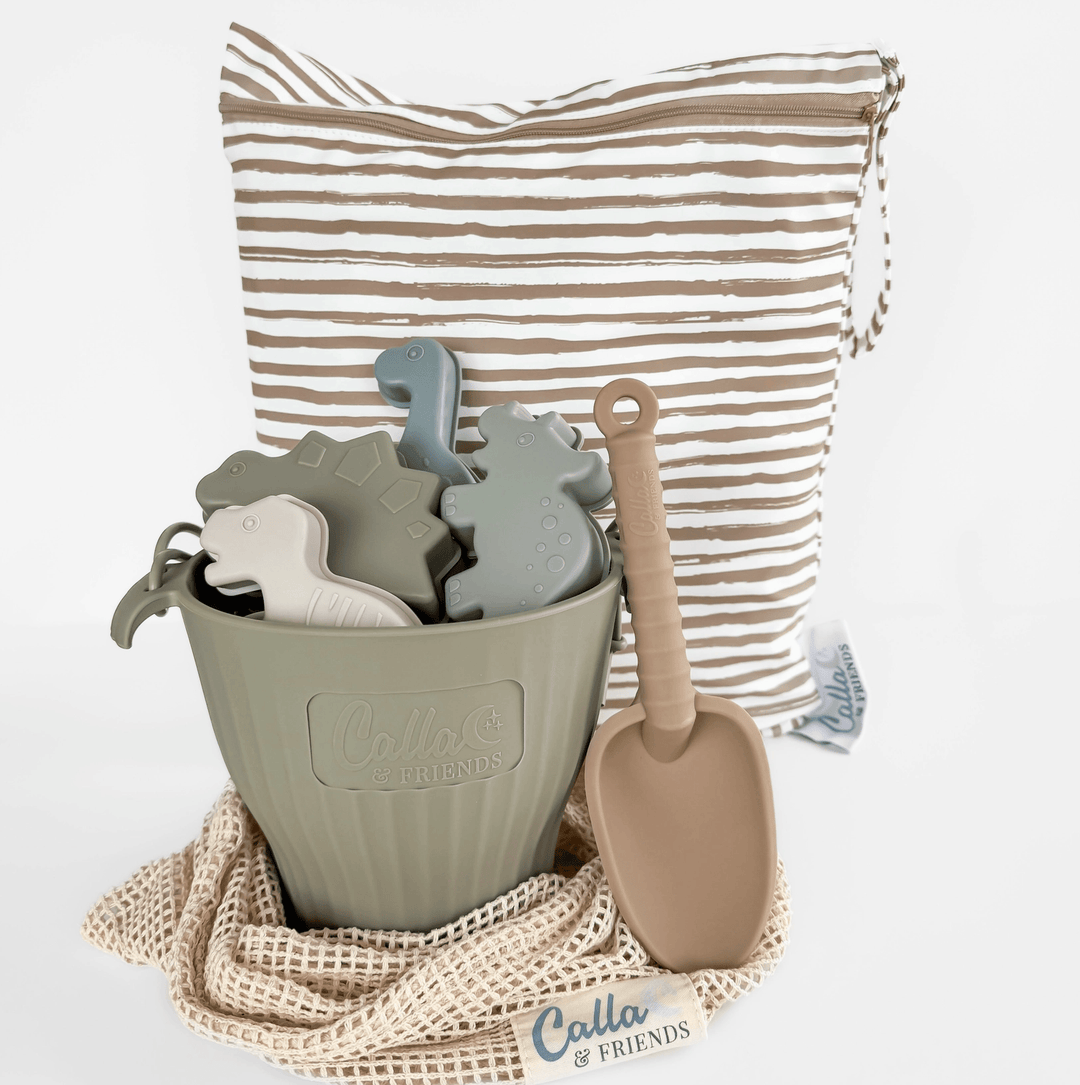 Children's toy set with a green bucket, dinosaur-shaped molds, and a sand shovel on a white background.