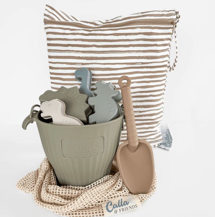 Children's toy set with a green bucket, dinosaur-shaped molds, and a sand shovel on a white background.