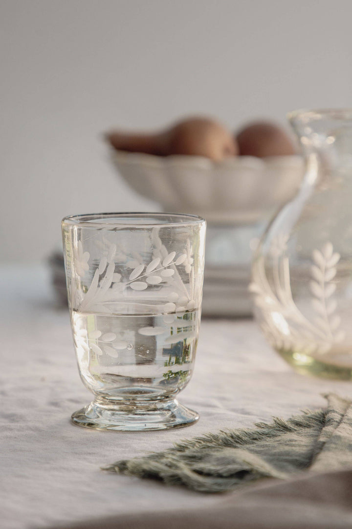 Etched recycled glass drinking glass on white background.