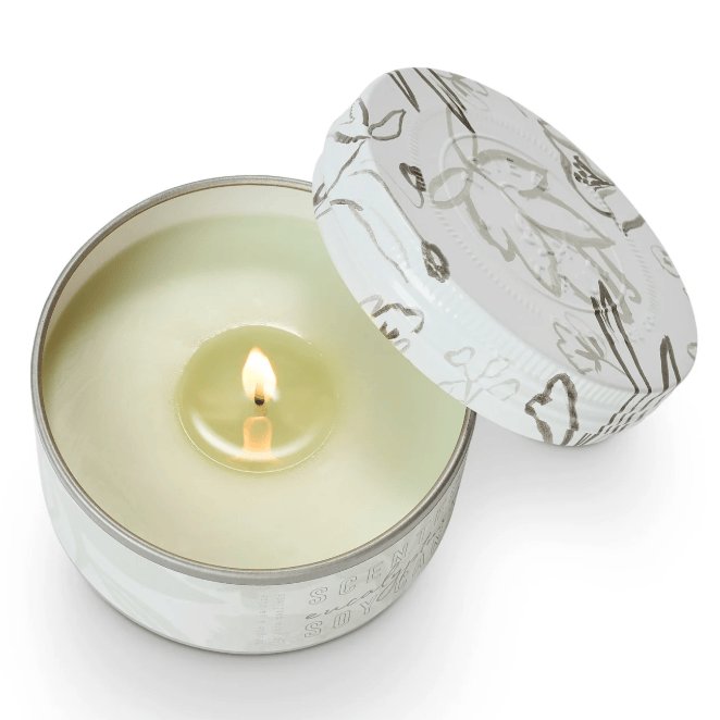 Candle in a decorative tin with floral design on a white background