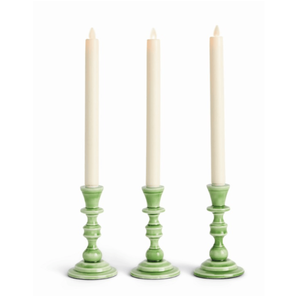 Three green candle holders with white candles on a white background