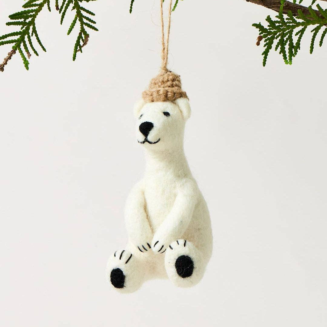 Polar bear ornament with a hat hanging on a branch
