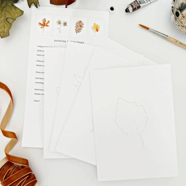 Sheet of paper with printed text and paintable leaf illustrations on a white surface with decorative items.