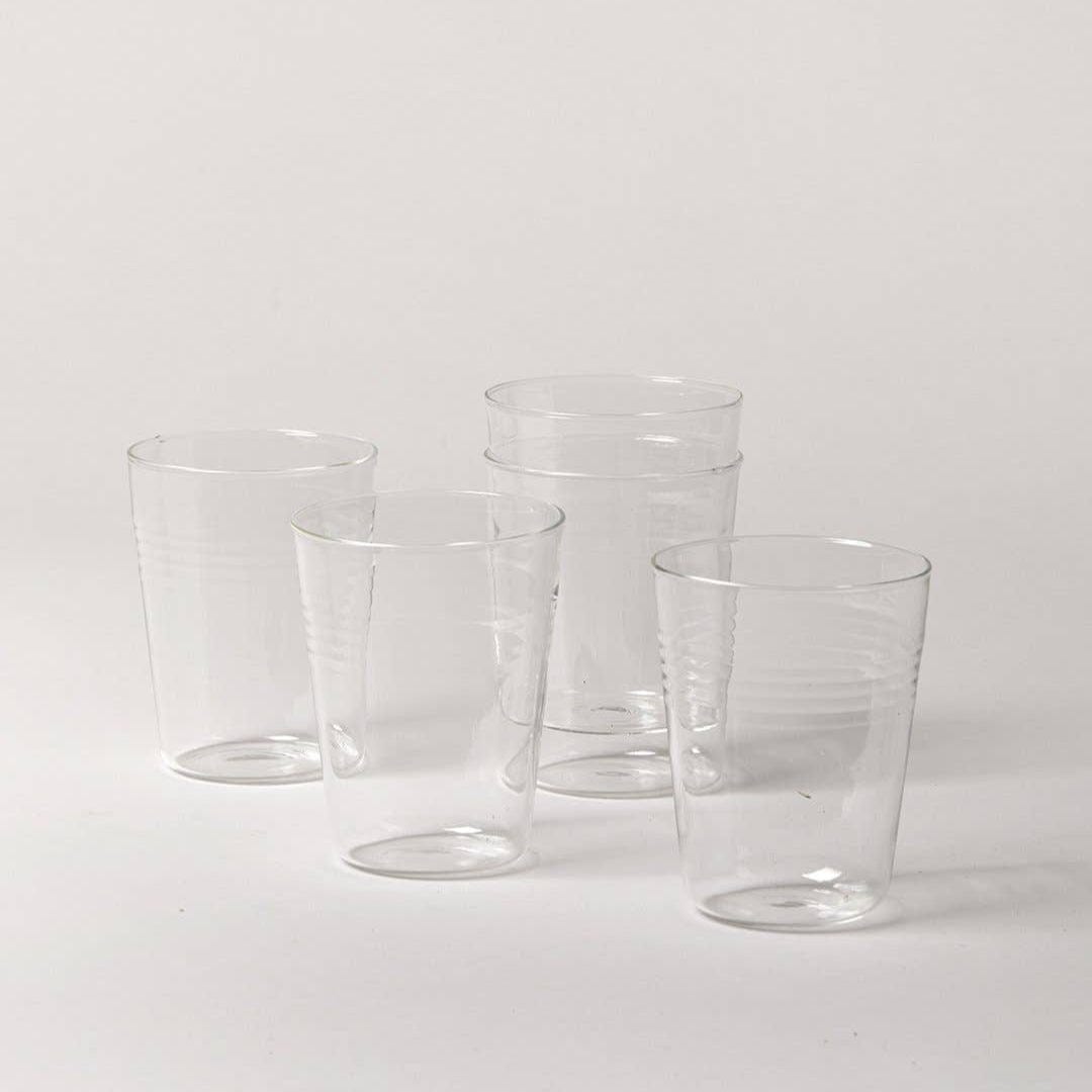 Set of five clear drinking glasses on a white background