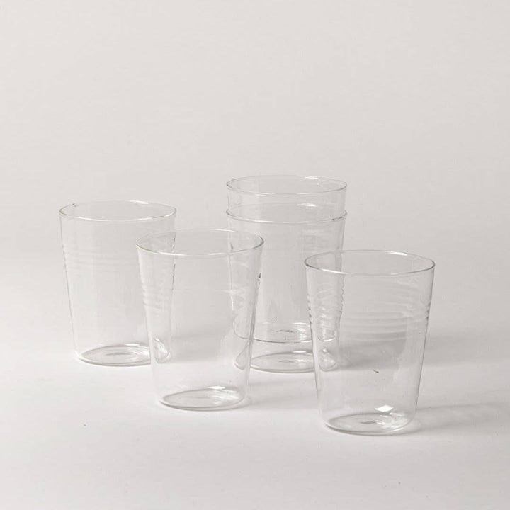 Set of five clear drinking glasses on a white background