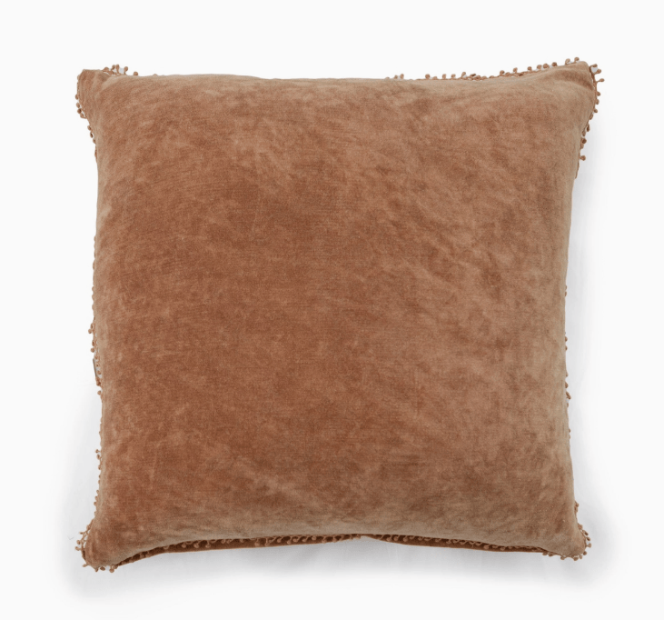 A square tan velvet throw pillow with decorative fringed edges, shown against a plain white background.