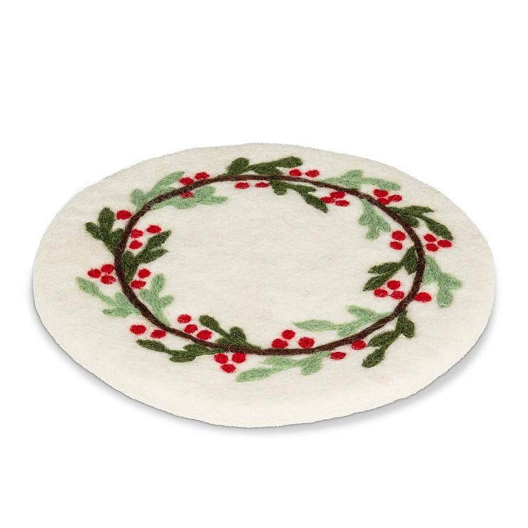 A round white felt trivetfeaturing a hand-picked holly wreath design with green leaves, red berries, and brown branches, set against a plain white background.