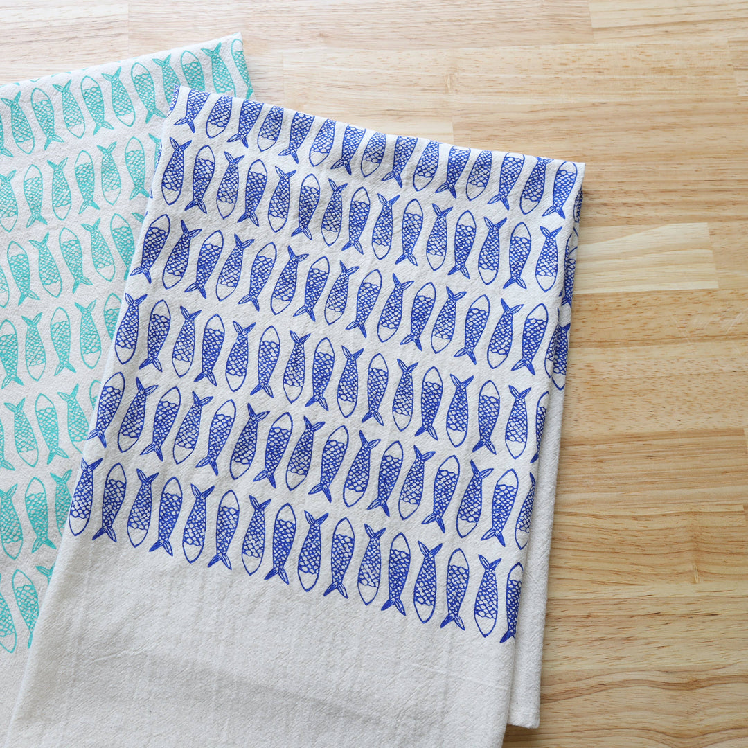 Two fabric towels with fish patterns on a wooden surface