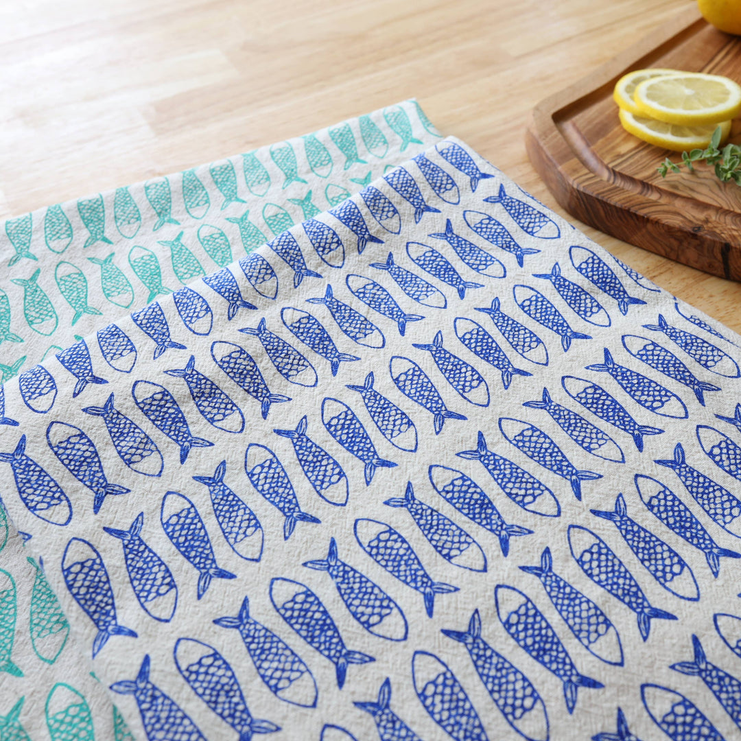 Tea towel with fish pattern on a wooden surface with lemons and herbs