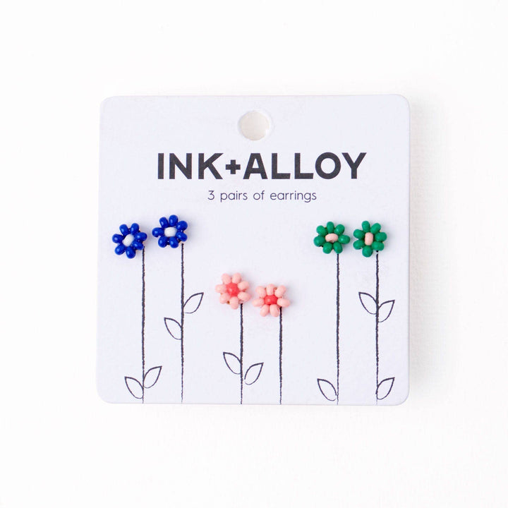 Ink+Alloy flower-shaped earrings on a white card with floral design