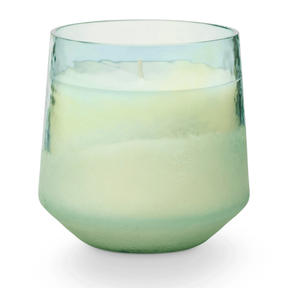 Candle in blue glass container on white background.
