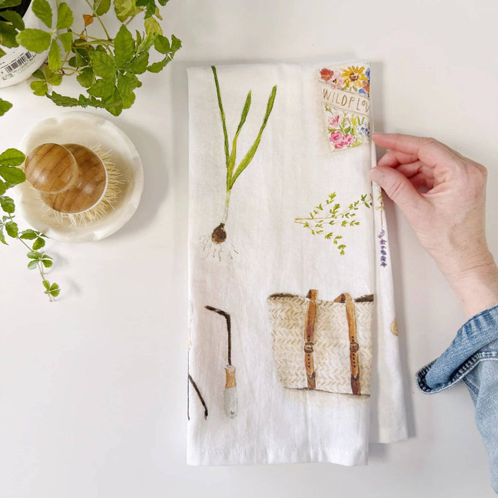 Hand holding a floral-patterned book with a white cover on a light surface.
