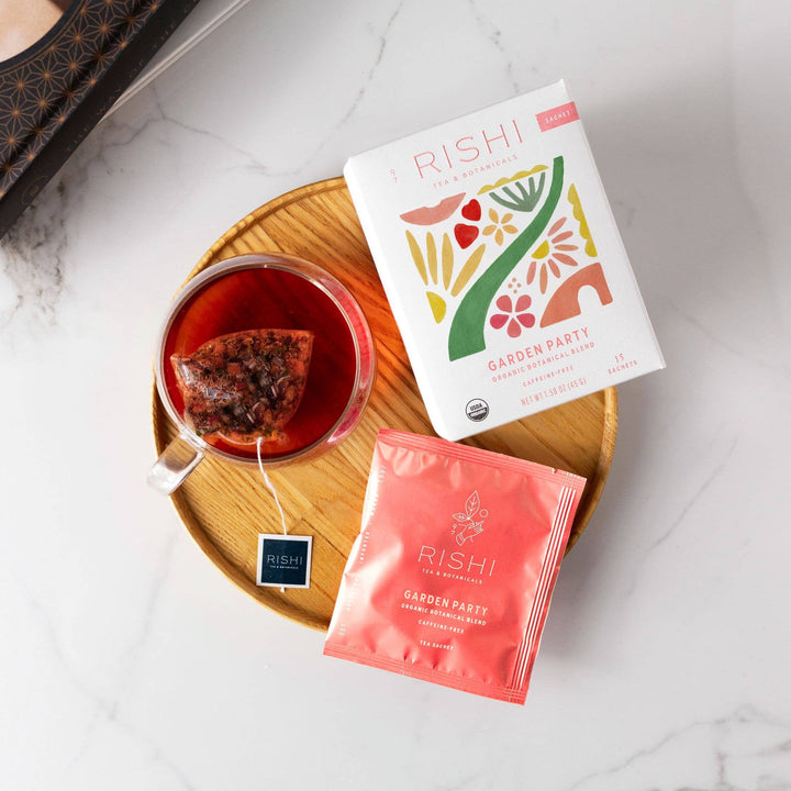 Rishi tea packaging with a cup of tea on a wooden coaster on a white surface