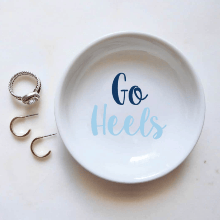 White trinket dish with 'Go Heels' text and rings on a white background