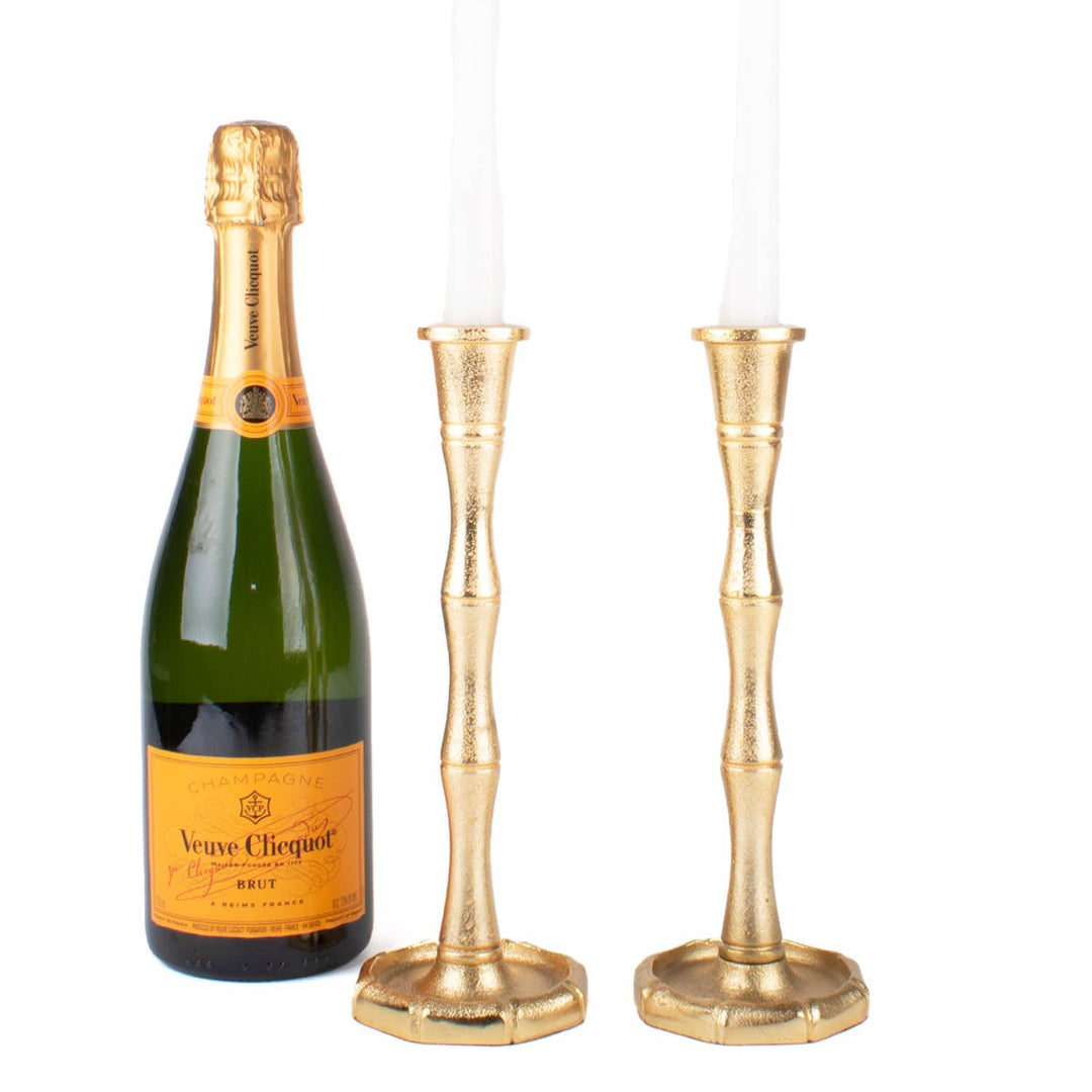 Bottle of Veuve Clicquot champagne with two gold candle holders on a white background