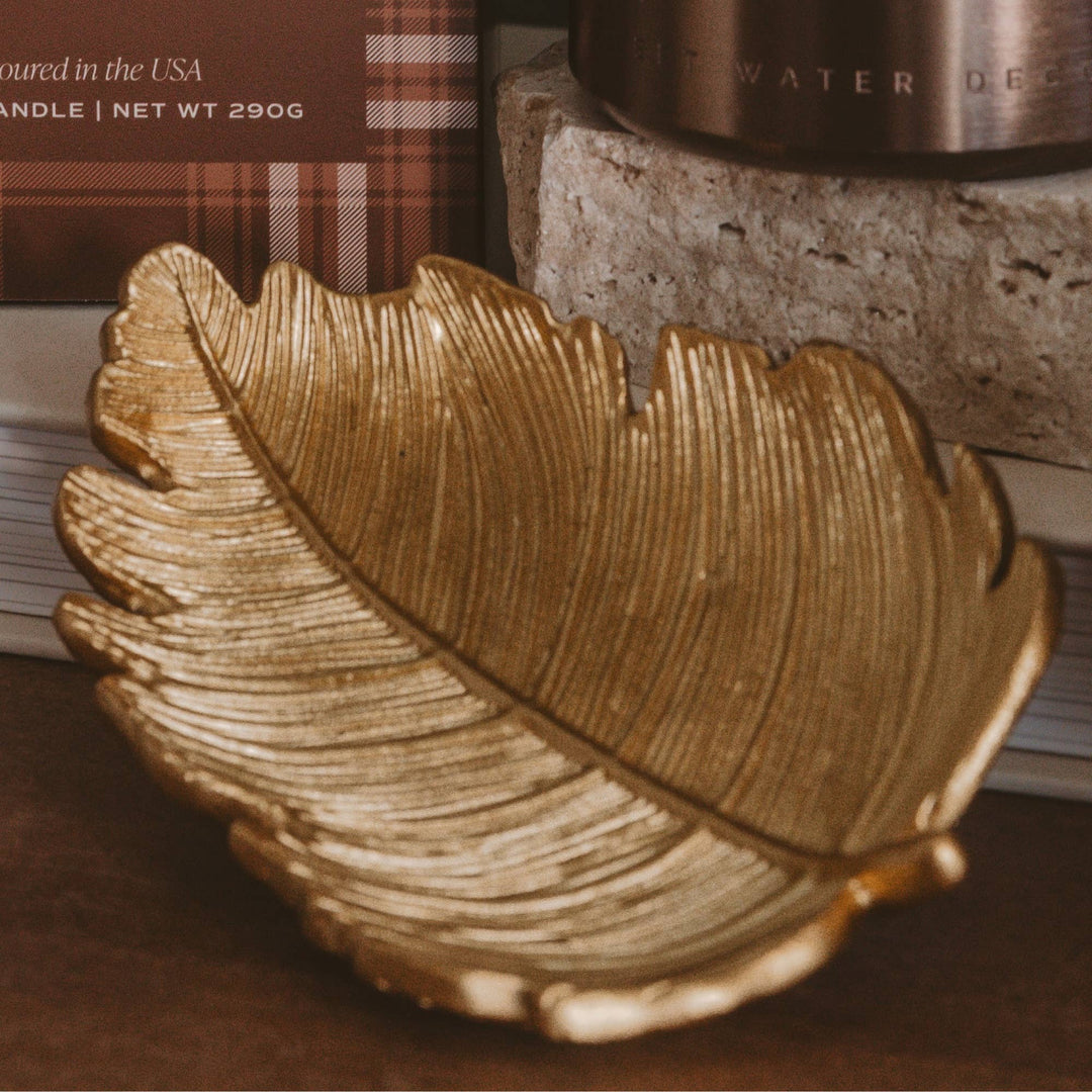 Gold leaf-shaped decorative item on a brown surface with blurred text in the background