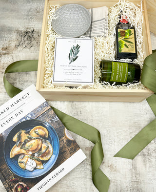 Filled with the most delicious olive oil from Nina's Olivar, a fresh scented candle from Rewined Candles, rustic artisanal crackers, a ceramic dipping bowl, black and cream kitchen towel and topped with one of our favorite influencers, Tieghan Gerard, who makes the most amazing looking dishes! Packed in a square pine box and tied with an olive green satin ribbon. Wonderful wedding gift, closing or holiday gift; also great for any new housewarming.