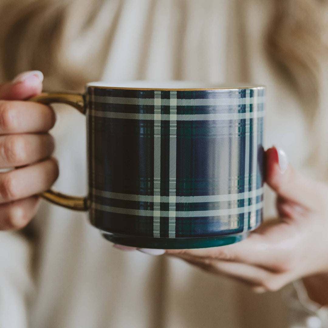 Person holding a plaid mug with steam rising, blurred background