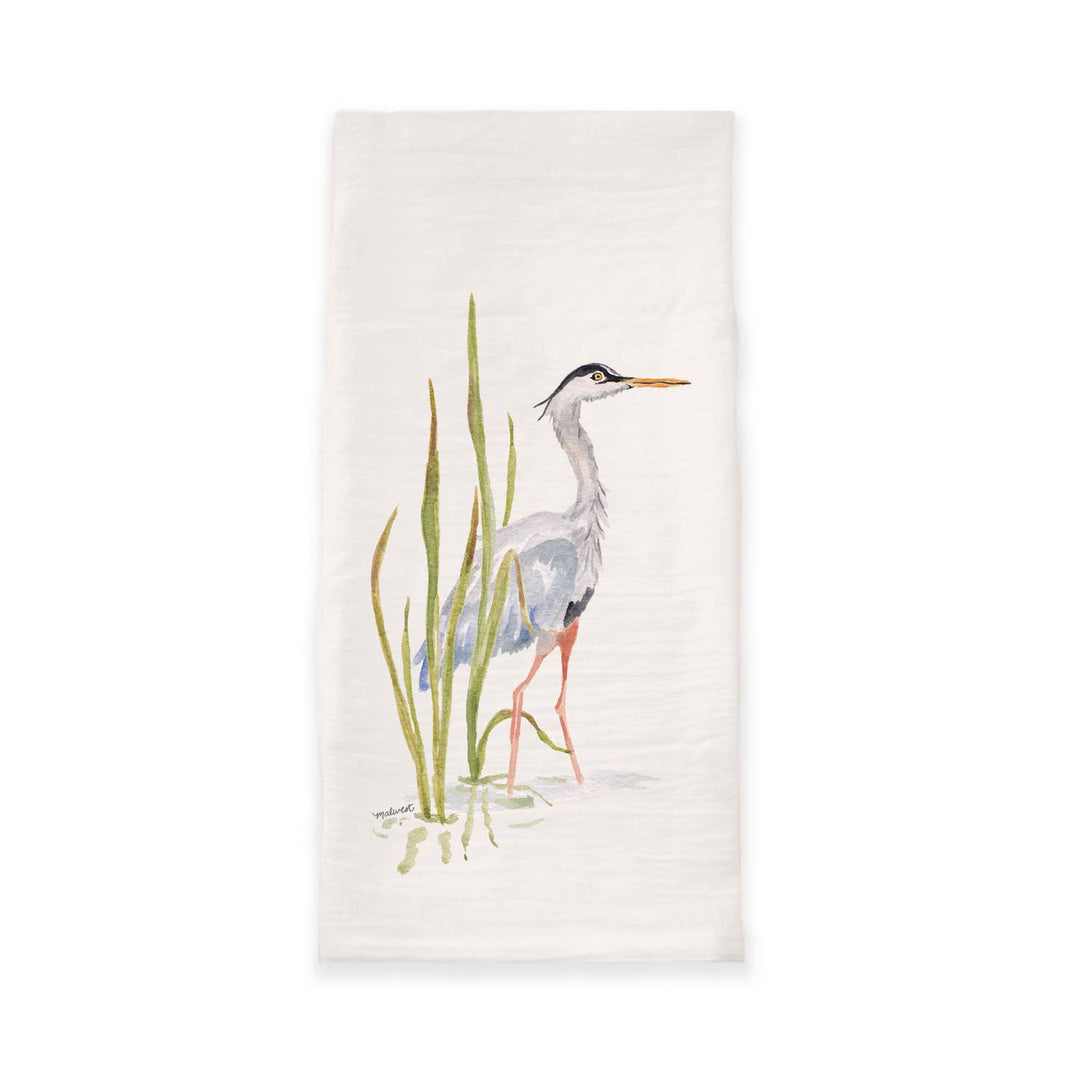 An off-white cotton tea towel featuring a watercolor illustration of a grey heron standing among green reeds.