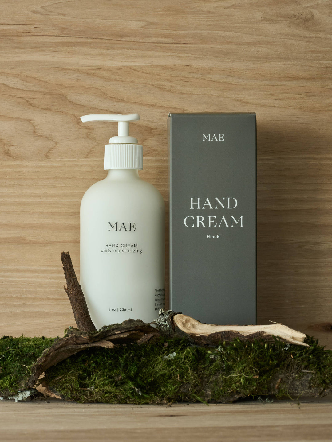 Mae hand cream bottle and packaging on a wooden surface with moss
