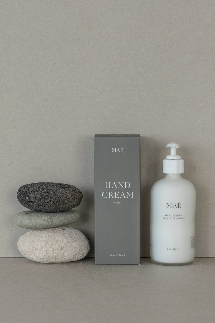 Hand cream bottle and packaging with stones on a neutral background