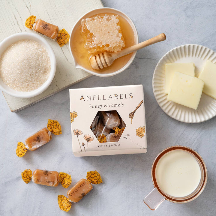Anellabees honey caramels with a bowl of honey, sugar, and a mug on a light surface.