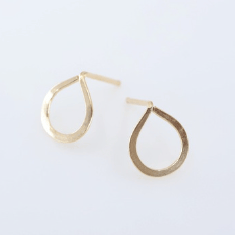Gold teardrop earrings on a light gray background