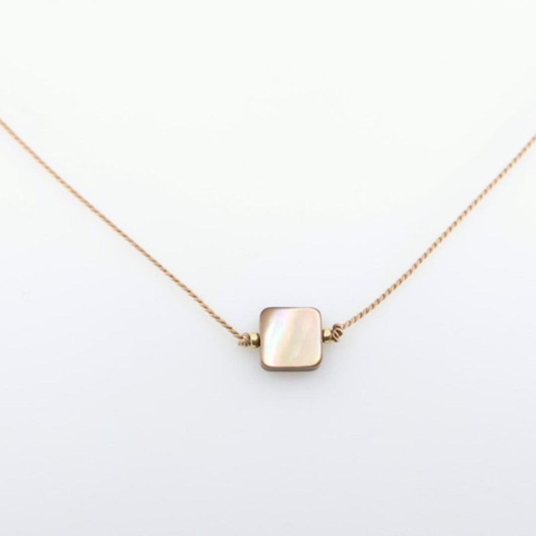Gold necklace with a square pendant on a white background