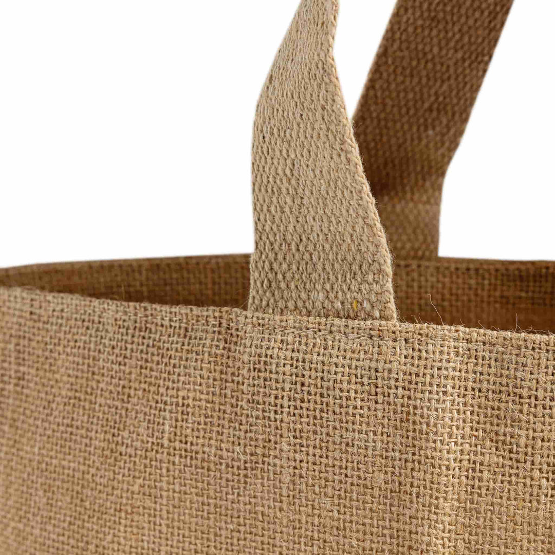 Close-up of a brown jute bag with handles on a white background