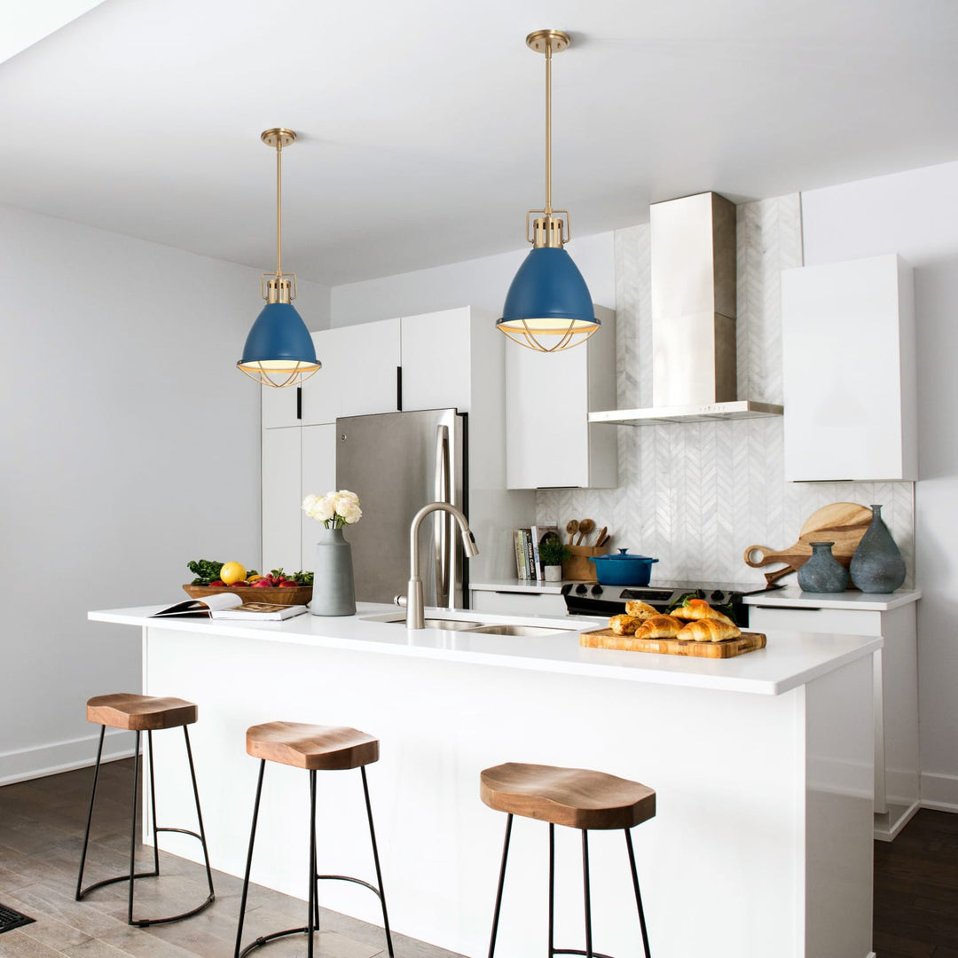 A modern kitchen interior with two blue pendant lights hanging above a white island. The kitchen has white cabinets, a stainless steel refrigerator, a white range hood, and three wooden bar stools at the island.