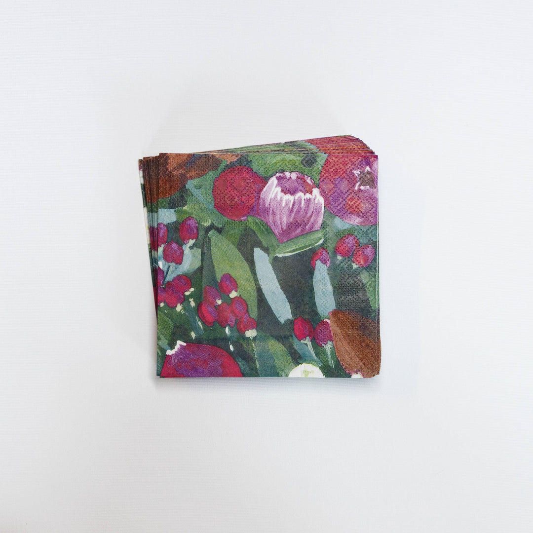 A stack of square paper napkins featuring a colorful floral and botanical pattern with pink, red, green, and purple tones, set against a plain white background.