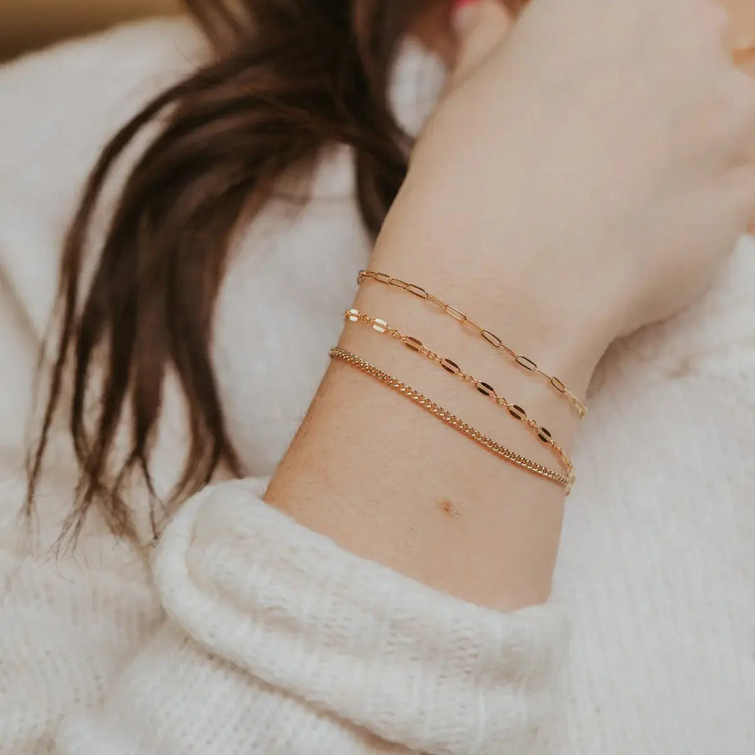 Close-up of a person's arm wearing gold bracelets with a blurred background