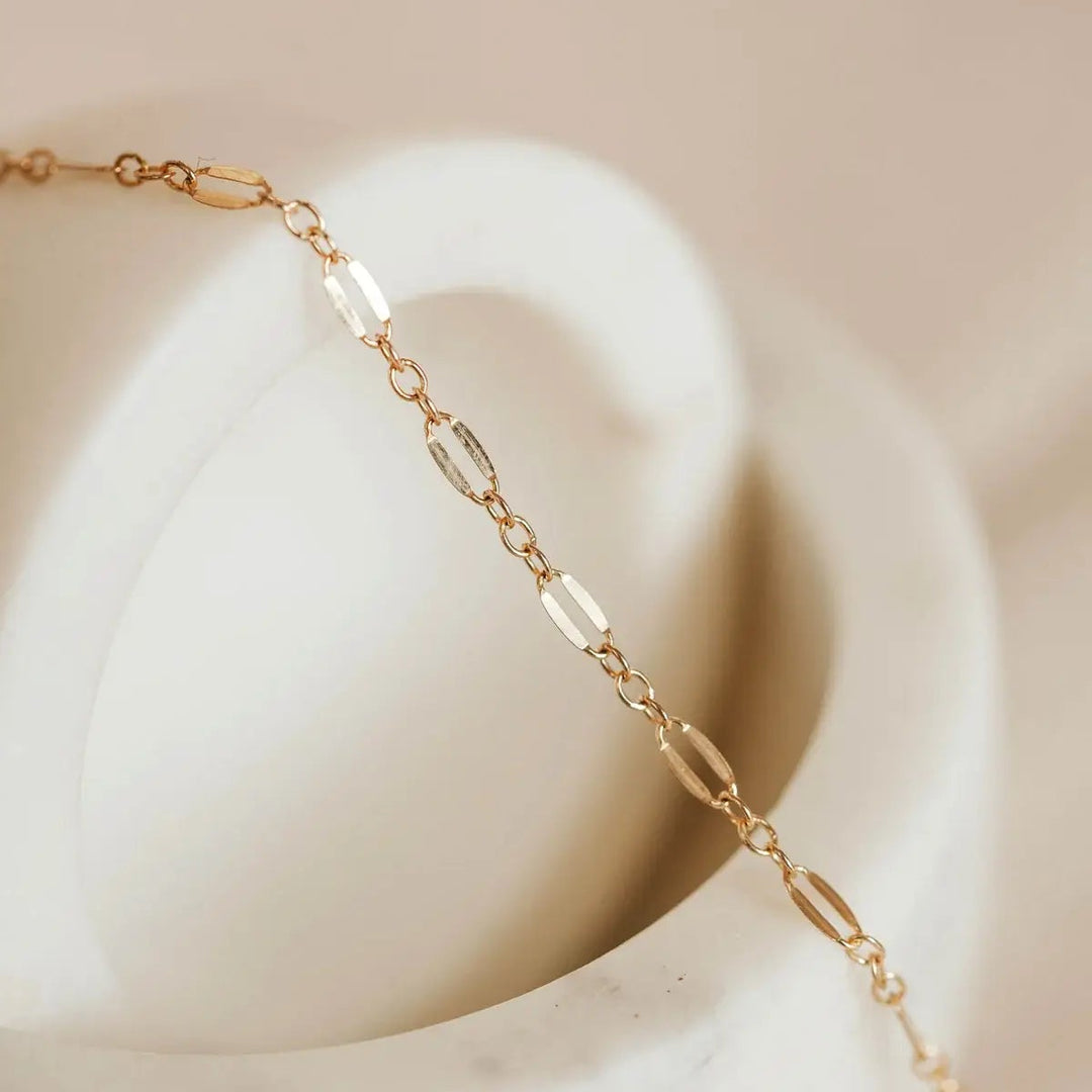 Gold chain bracelet on a white surface