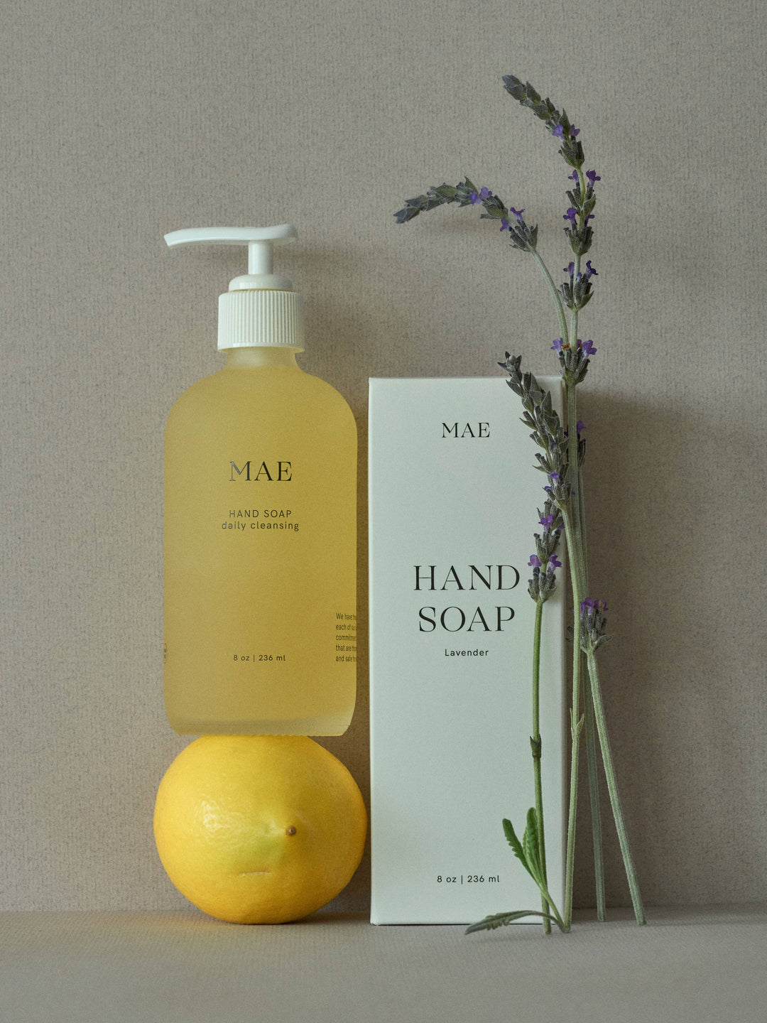 Hand soap bottle, packaging, lemon, and lavender on a neutral background