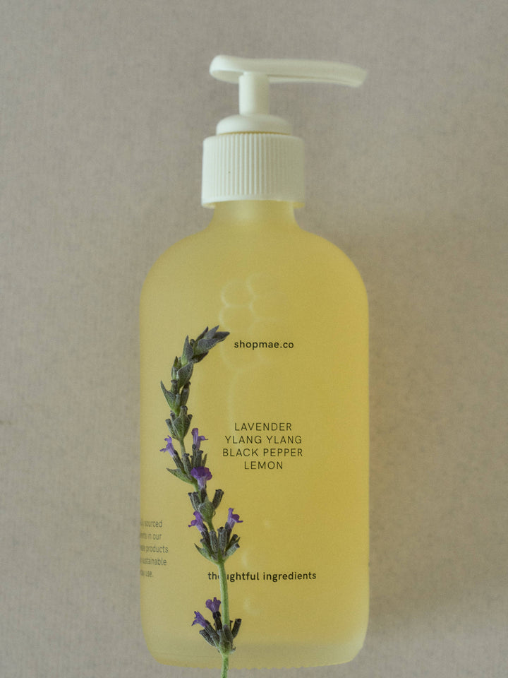 Yellow bottle with pump and lavender sprig on a beige background