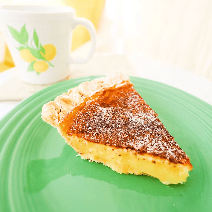 Slice of pie on a green plate with a cup in the background