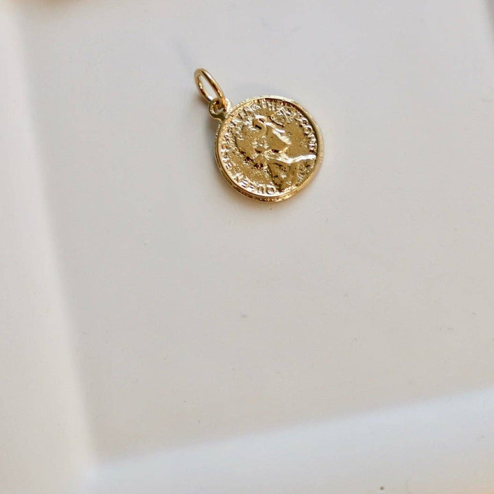 Gold pendant on a white ceramic dish with a bow