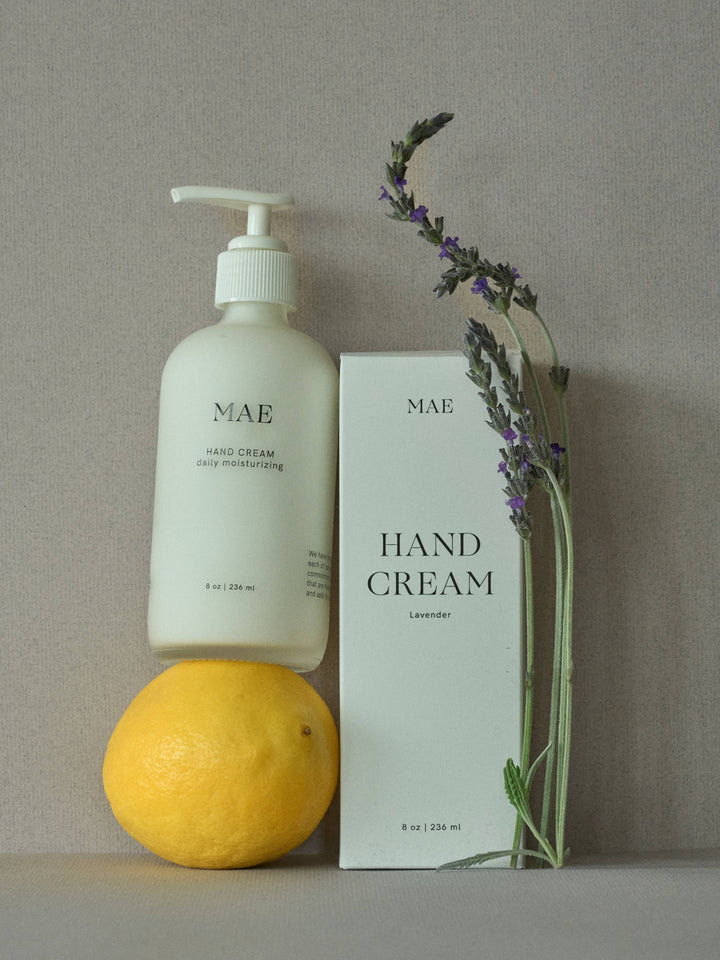 MAE hand cream bottle and packaging with a lemon and lavender sprig on a neutral background