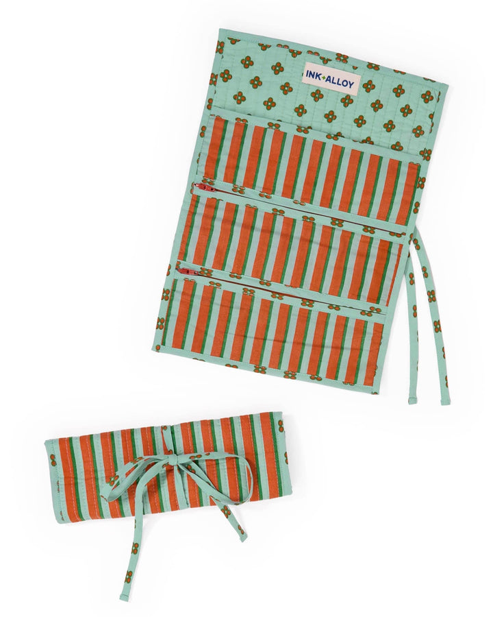 A fabric organizer pouch with a mint green and orange striped pattern, featuring a small gold floral motif and a visible 'INK-ALLOY' brand label. The pouch is shown both open and rolled up on a clean white background.