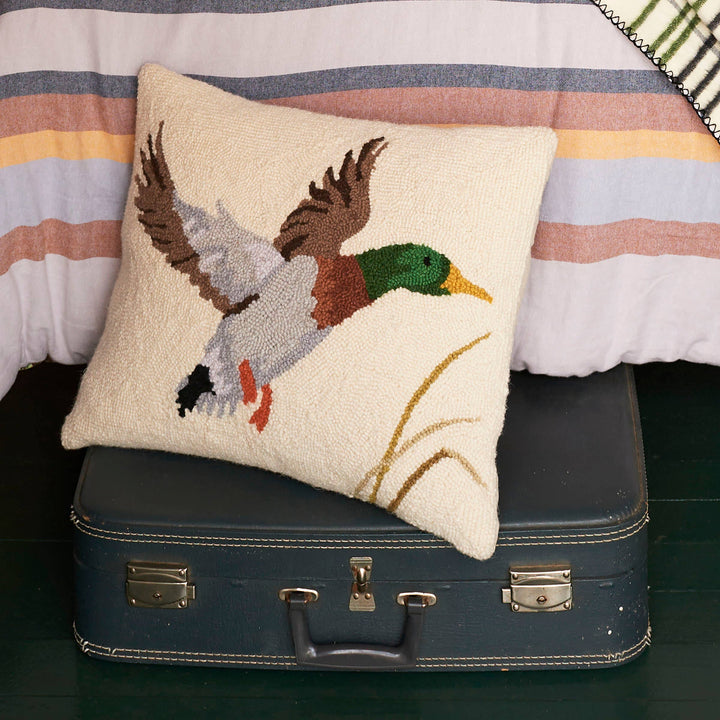 Decorative pillow with a duck design on a vintage suitcase