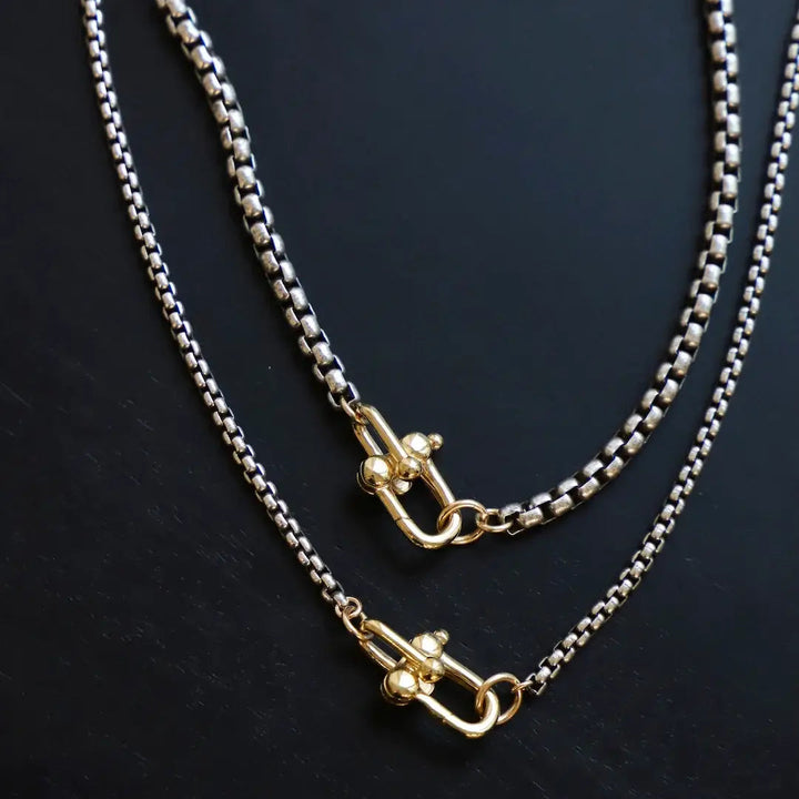 Two gold necklaces on a dark surface