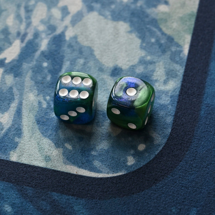 Two green dice with white dots on a blue textured surface