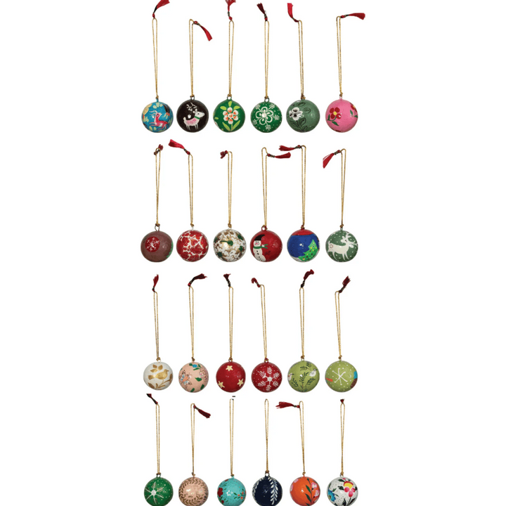 A set of 24 round Christmas ornaments arranged in four rows of five on a plain white background. Each ornament has a different festive design, including reindeer, snowflakes, stars, and holiday patterns in various colors, with gold hanging loops and small red ribbons.