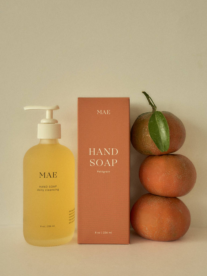 Mae hand soap bottle and packaging with oranges on a beige background