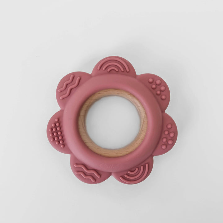 Pink flower-shaped teething ring on a white background