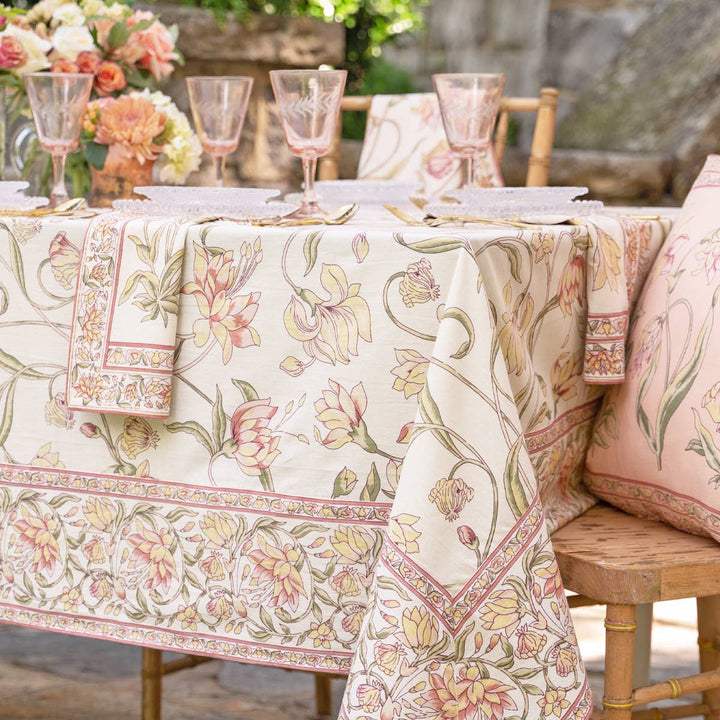 Outdoor table setting with floral tablecloth and chairs.